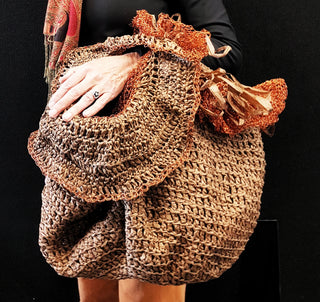 A person holding a bag made from unique gathered material.