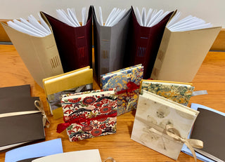 Books on a table in a range of different sizes, all with unique covers and bindings of varying colours and patterns.