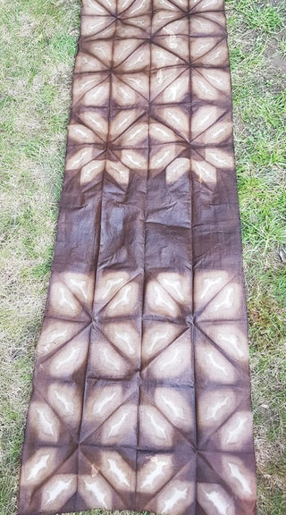 A long piece of fabric eco-dyed brown with plants in a tessellating pattern.