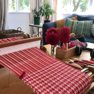 Hand loom with a half-finished red washcloth or dishcloth.
