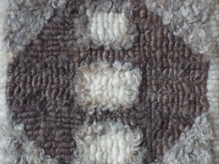 A natural grey and brown Heirloom Hooked Fleece Rug in an hexagonal pattern, close enough to see the fibres of the wool.