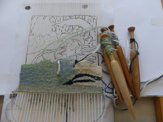 An in-progress tapestry weaving following a sketched design.