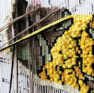 Close-up of a green and yellow tapestry in progress.