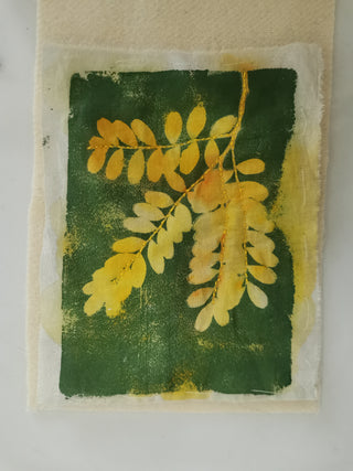 A Textile Collage artwork with yellow leaves printed on green and white fabric.
