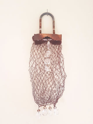 An artwork made to look like a long handbag, made from interlocking metal.