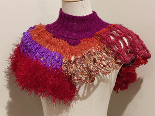 A crochet shawl-like neckpiece made with red and purple yarn.