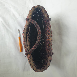 Top view of a traditional Māori Kete basket woven with purple brown Harakeke (NZ Flax), next to a pen for scale.
