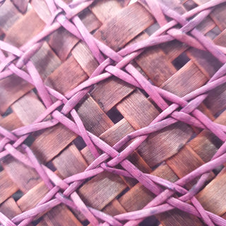 Close-up of the traditional Māori Kete basket woven with purple brown Harakeke (NZ Flax), showcasing it's intricate pattern.