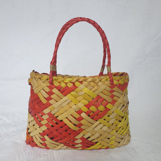 Traditional Māori Kete basket woven with light brown, red, orange and yellow Harakeke (NZ Flax).