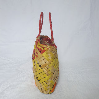 Side-view of a traditional Māori Kete basket woven with light brown, red, orange and yellow Harakeke (NZ Flax).