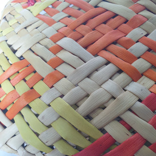 Close-up of a traditional Māori Kete basket woven with light brown, red, orange and yellow Harakeke (NZ Flax).