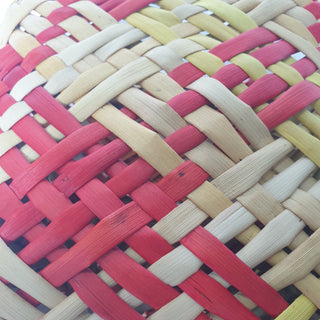 Close-up of a traditional Māori Kete basket woven with light brown, red, orange and yellow Harakeke (NZ Flax).