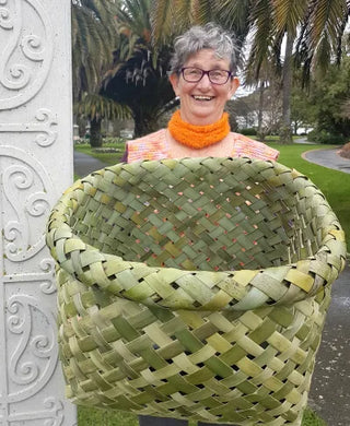 Harakeke (NZ Flax Weaving) tutor Evey Weavy smiling while holding a big basket woven from harakeke.