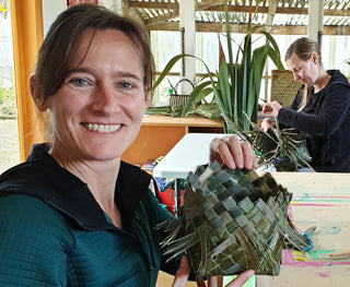 Student smiling, holding up their harakeke woven basket.